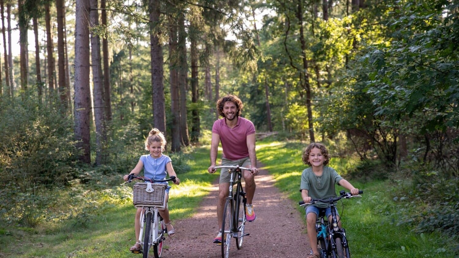 Kinderen samen met vader aan het fietsen in het bos nabij Westerbergen in Drenthe